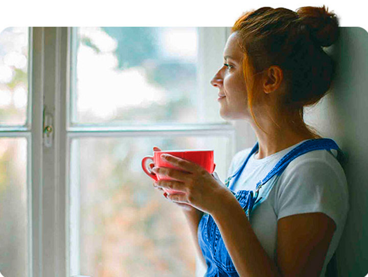 Chica sujetando taza de café mientras está en su hogar