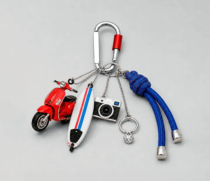Llavero con una moto, tabla de surf, cámara, anillo y cuerda en color rojo y azul