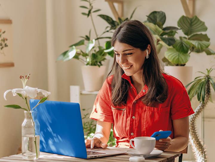 Chica joven trabajando con su ordenador portatil mientras toma café