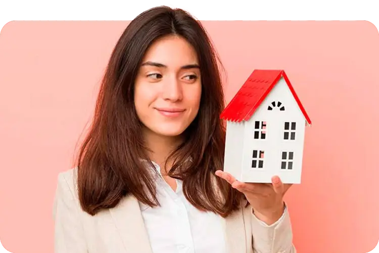 Mujer sosteniendo una casita de juguete mientras la mira