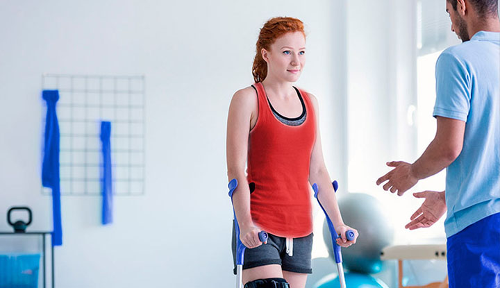 Mujer en rehabilitación mientras camina con sus muletas