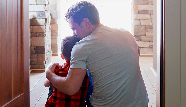 Un padre dando un beso en la cabeza a su hijo