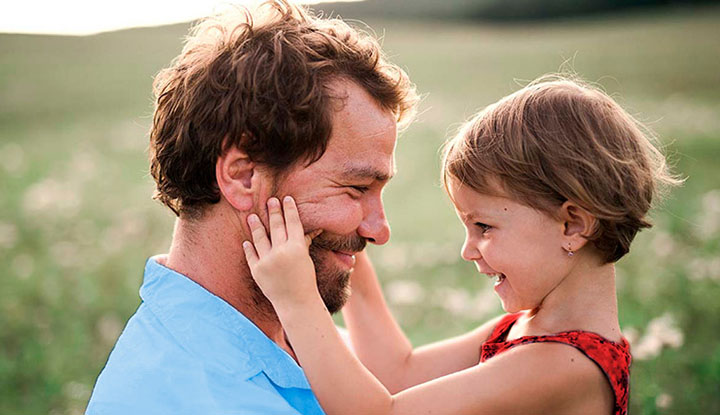 Una niña apretando los mofletes a su padre