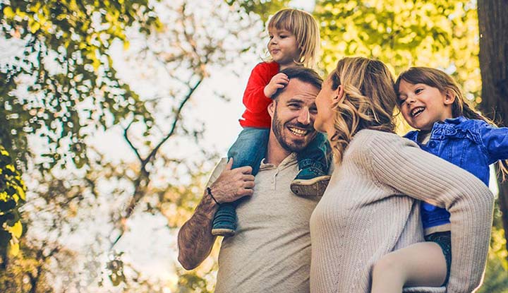 Una familia riendo mientras están caminando bajo los árboles