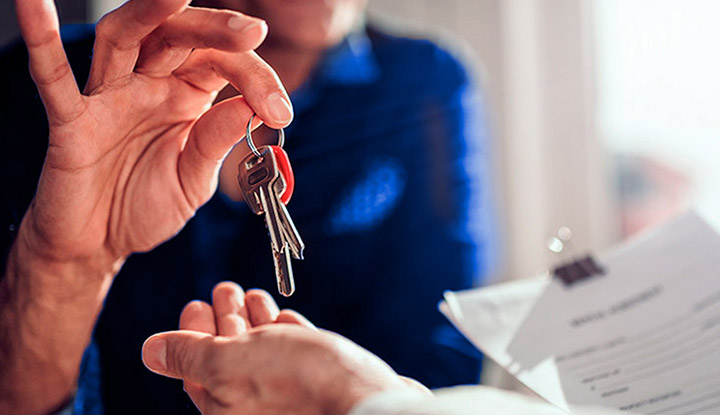 Hombre sonriente mientras sujeta las llaves de su propiedad