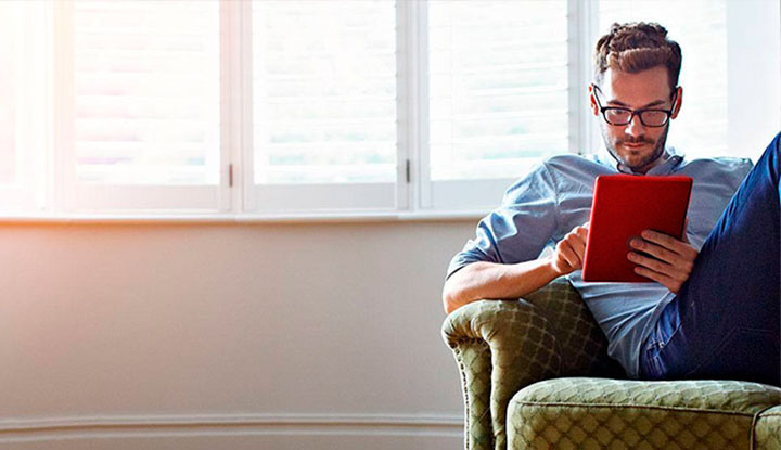 Hombre revisando su tablet mientras está sentado en el sofá