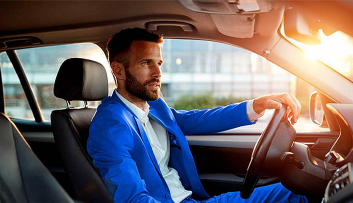 Hombre joven trajeado conduciendo su coche