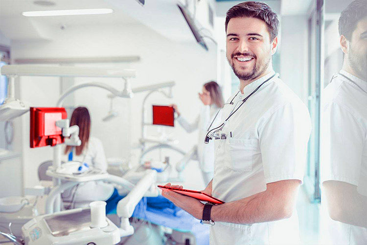 Dentista sonriente sosteniendo el infomre del paciente, representando los servicios del seguro Caser Salud Dental