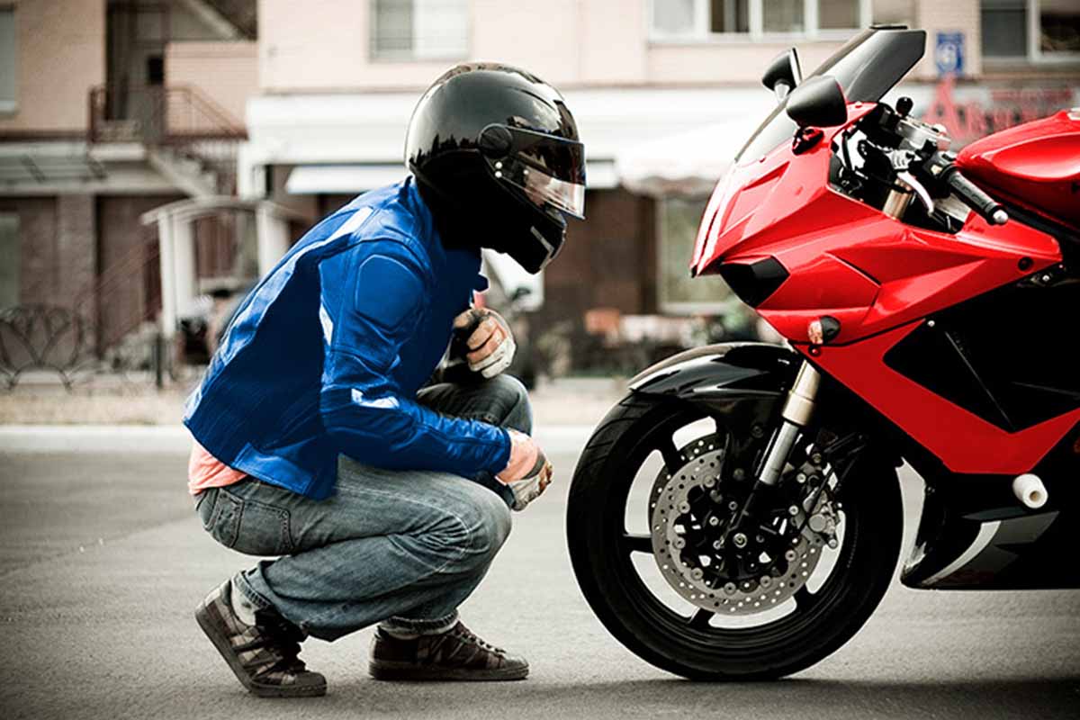 Hombre revisando la rueda de su moto