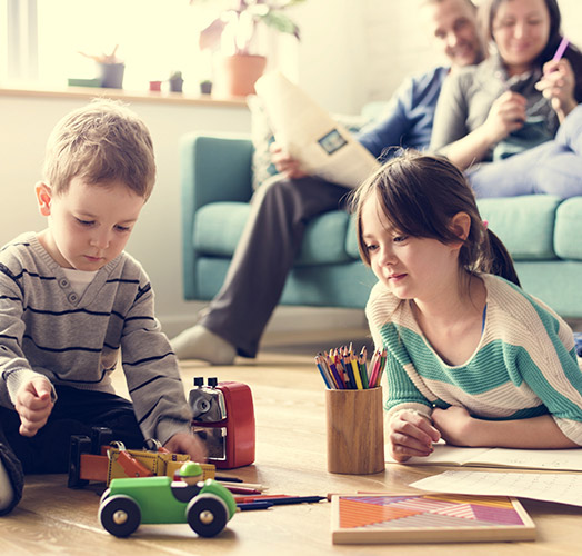 Pareja viendo a los hijos jugar en el comedor de su casa