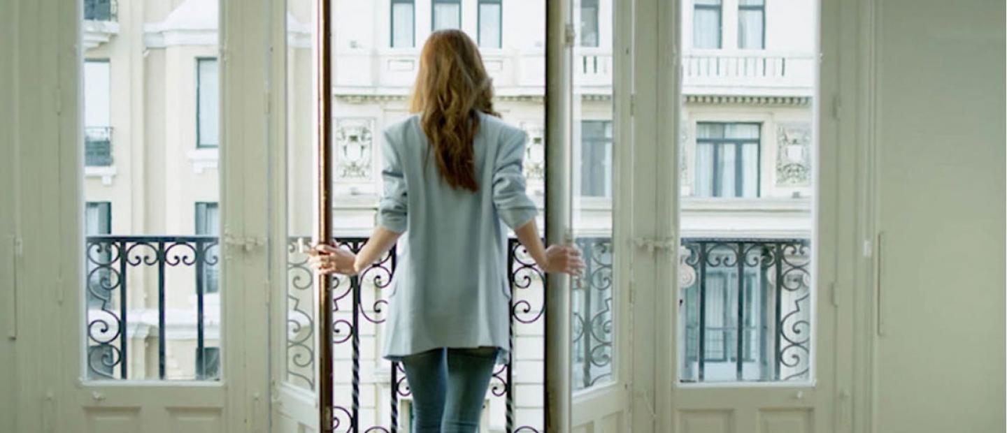 Imagen chica asomada al balcón de su casa