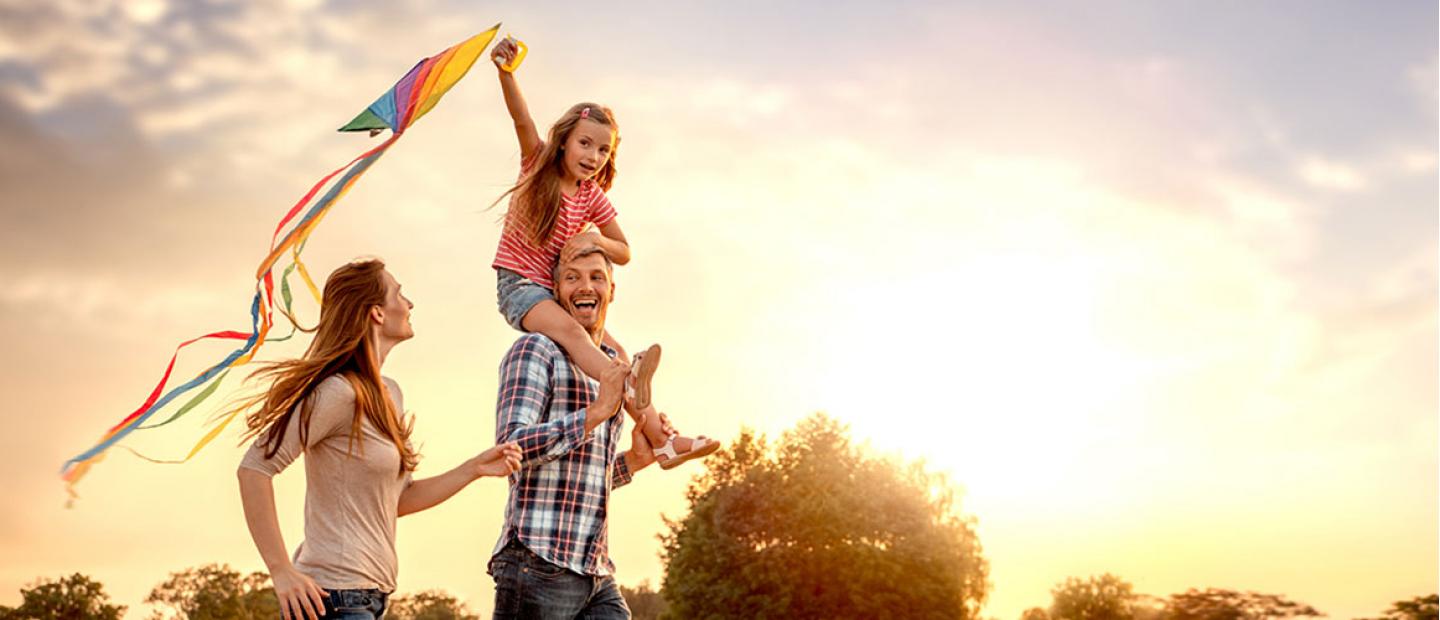 Una pareja y niña pequeña volando una cometa en el campo