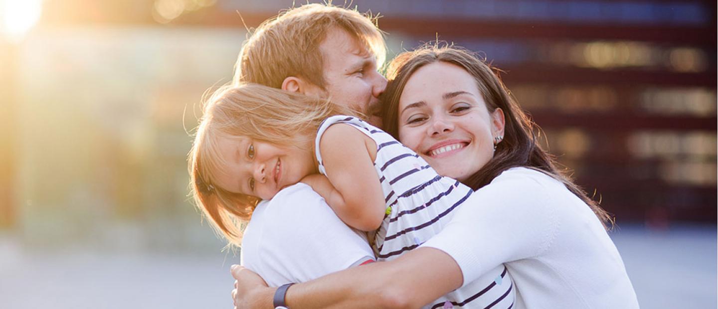 Imagen pareja con su hija abrazandose