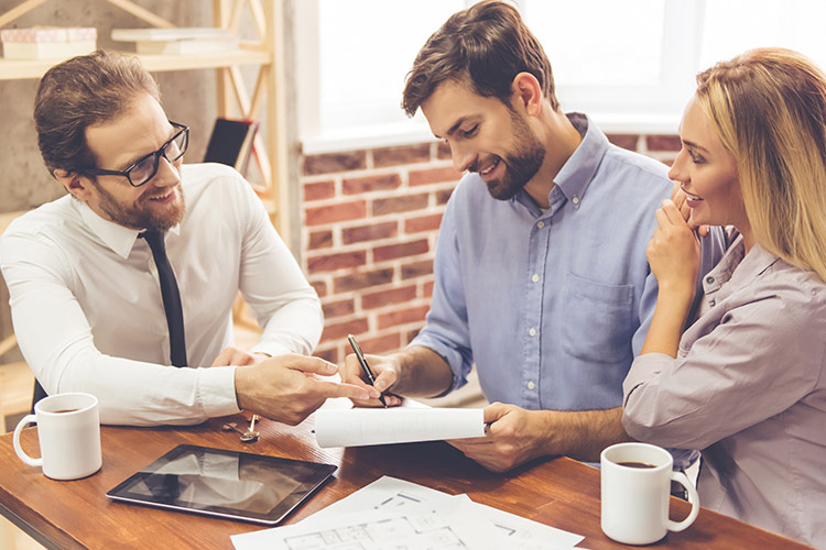 Imagen dos hombres y una mujer revisando papeles mientras toman café