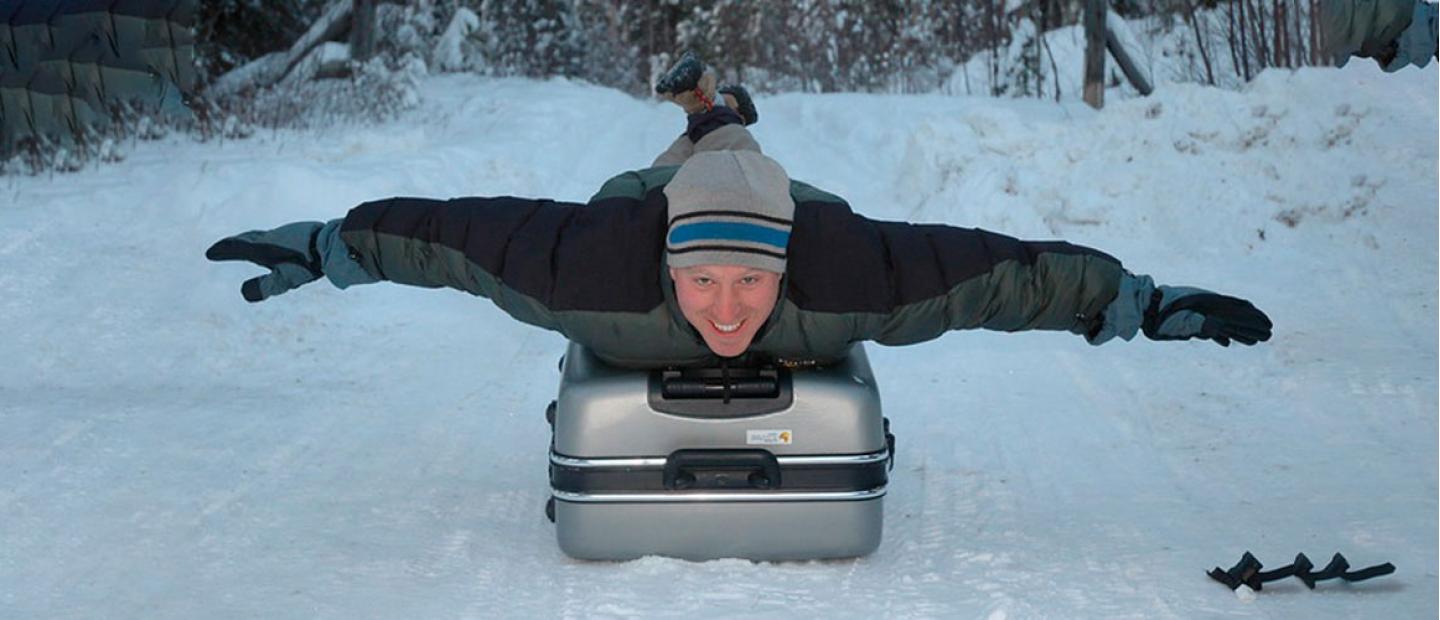 Imagen de un hombre sobre una maleta en la nieve