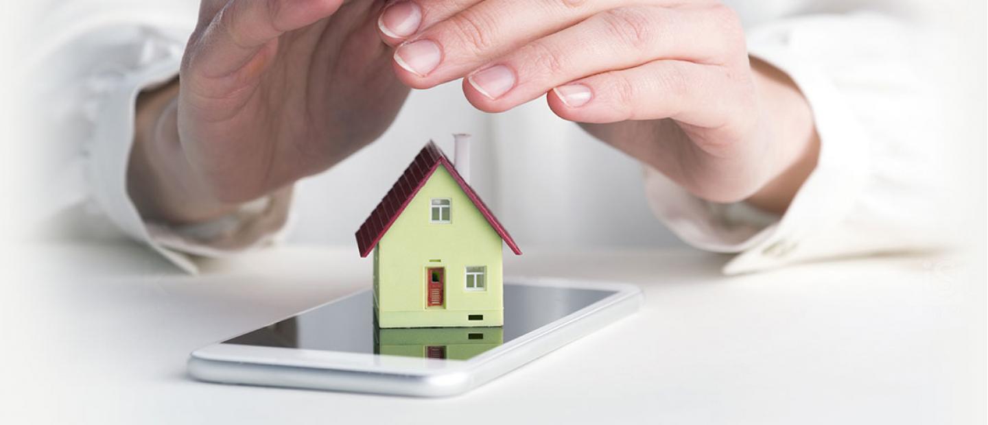 Imagen de una casa sobre un teléfono móvil protegida por unas manos