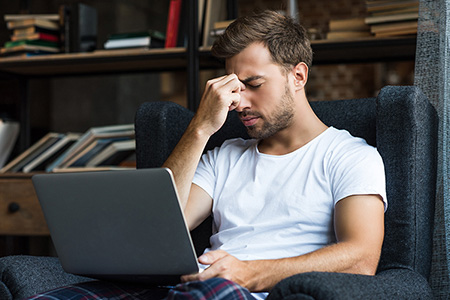 Imagen hombre pensativo en el sillón mientras trabaja con el ordenador