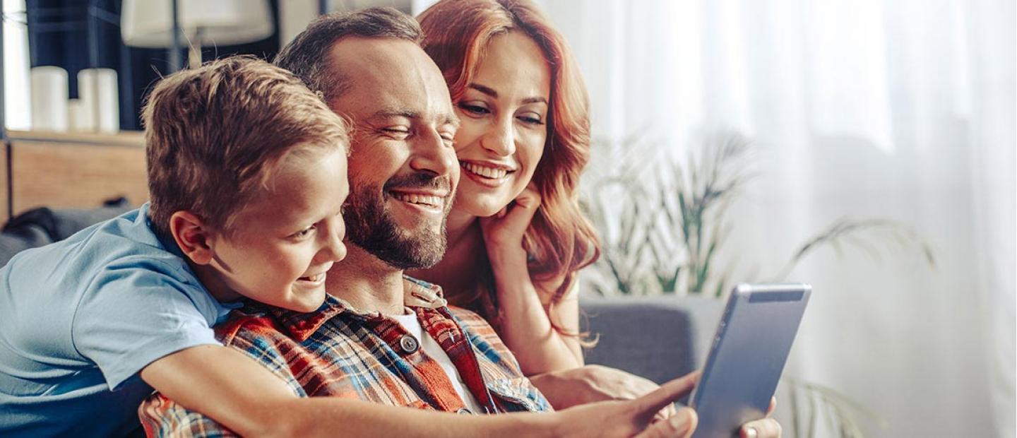 Imagen de una familia de un padre, madre e hijo sonriendo en el sofá