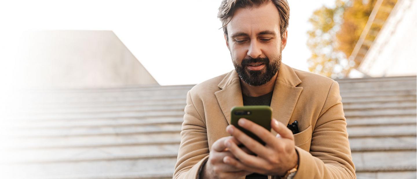Imagen hombre mirando el móvil en unas escaleras