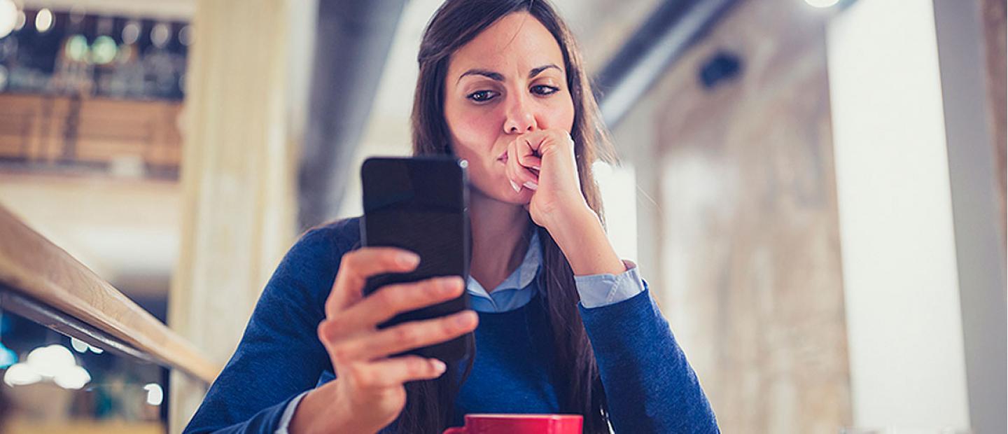 Imagen mujer pensando mientras mira su móvil