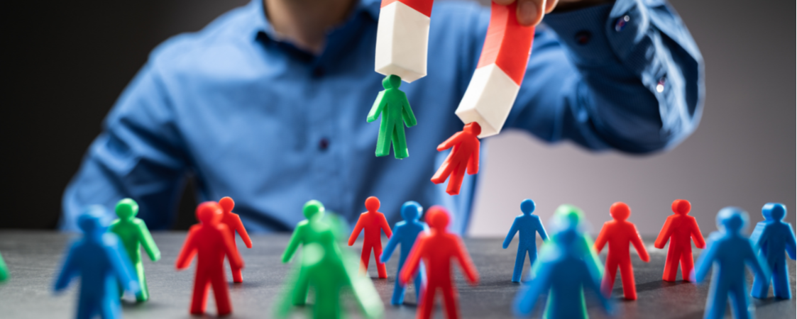 Manos con imanes atrayendo figuras humanas que representan captación de talento o clientes