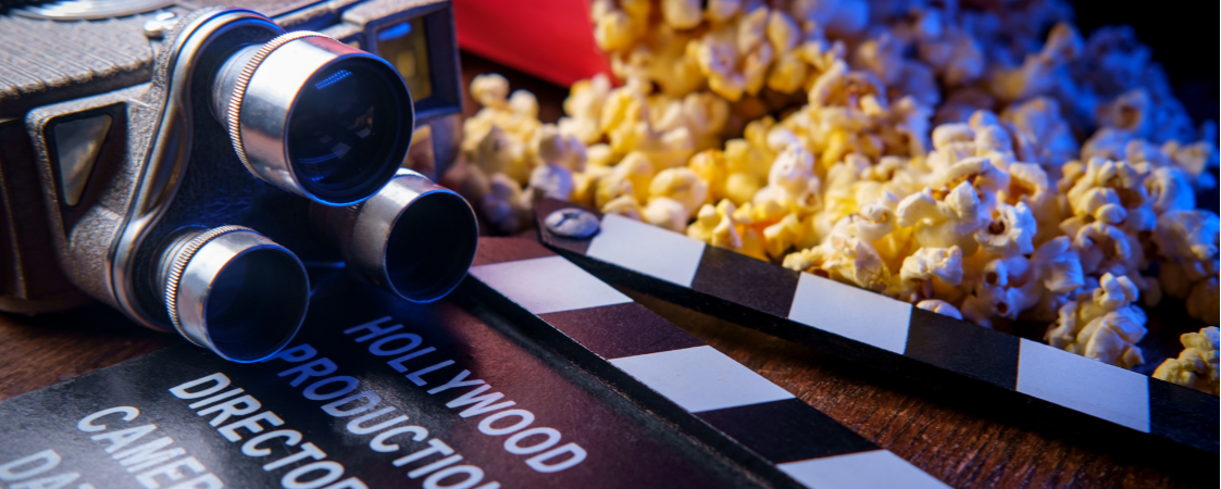 Cámara antigua y claqueta de cine junto a palomitas, representando producción cinematográfica