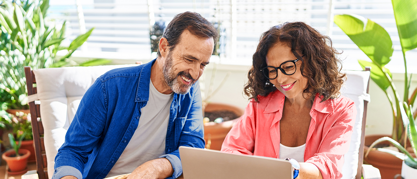 Pareja de hombre y mujer mirando el ordenador en la terraza de su casa