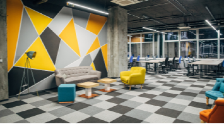 Oficina modular, con sillones y un área de descanso en colores amarillos y grises.