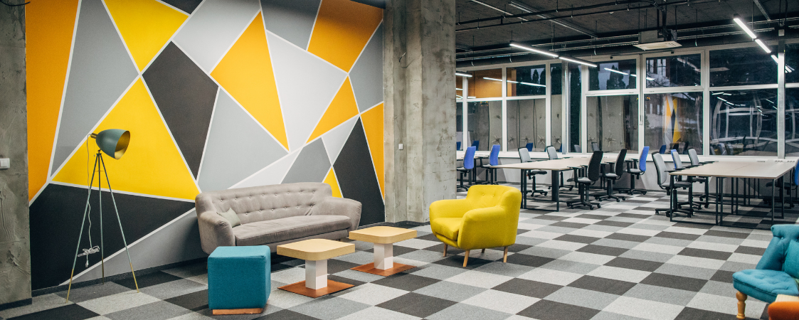 Oficina modular, con sillones y un área de descanso en colores amarillos y grises.