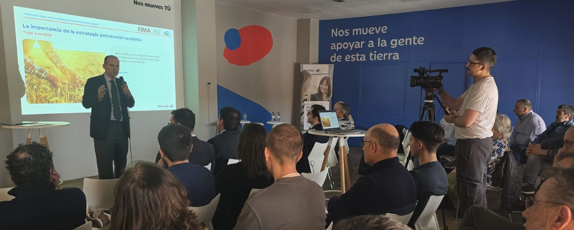 Ponente interviniendo frente a una pantalla. Público sentado escuchando.