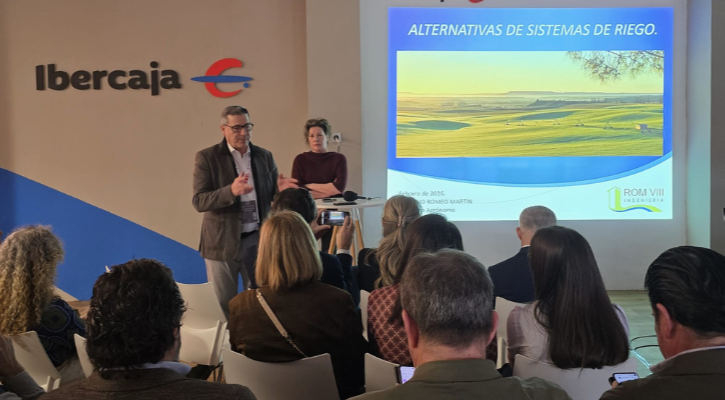 Ponentes hablando al público con una pantalla detrás con imagen de regadío