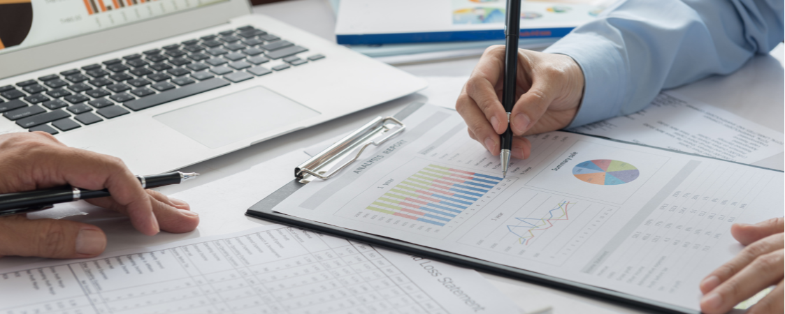 Hombre escribiendo en un papel datos con gráficas