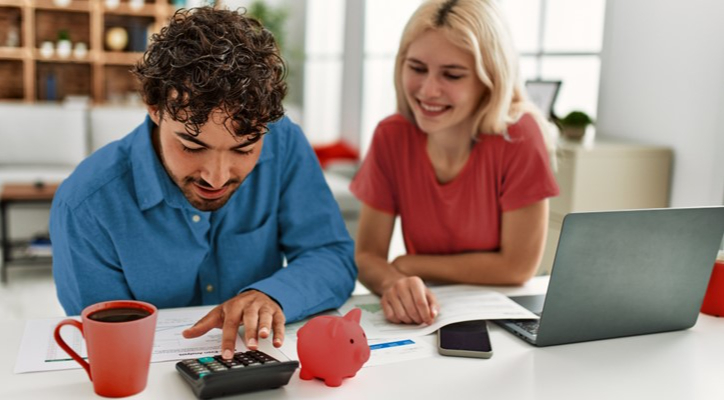 Un hombre y un mujer calculan sus ahorros en casa con un ordenador y una calculadora