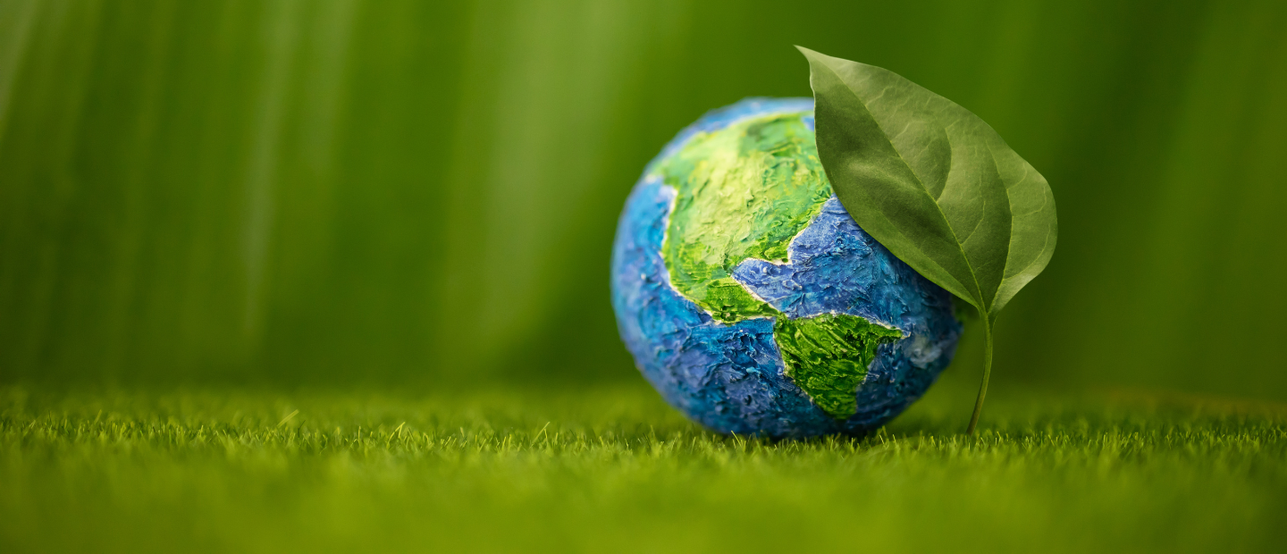 El planeta Tierra, cubierto parcialmente por una hoja verde y sobre césped