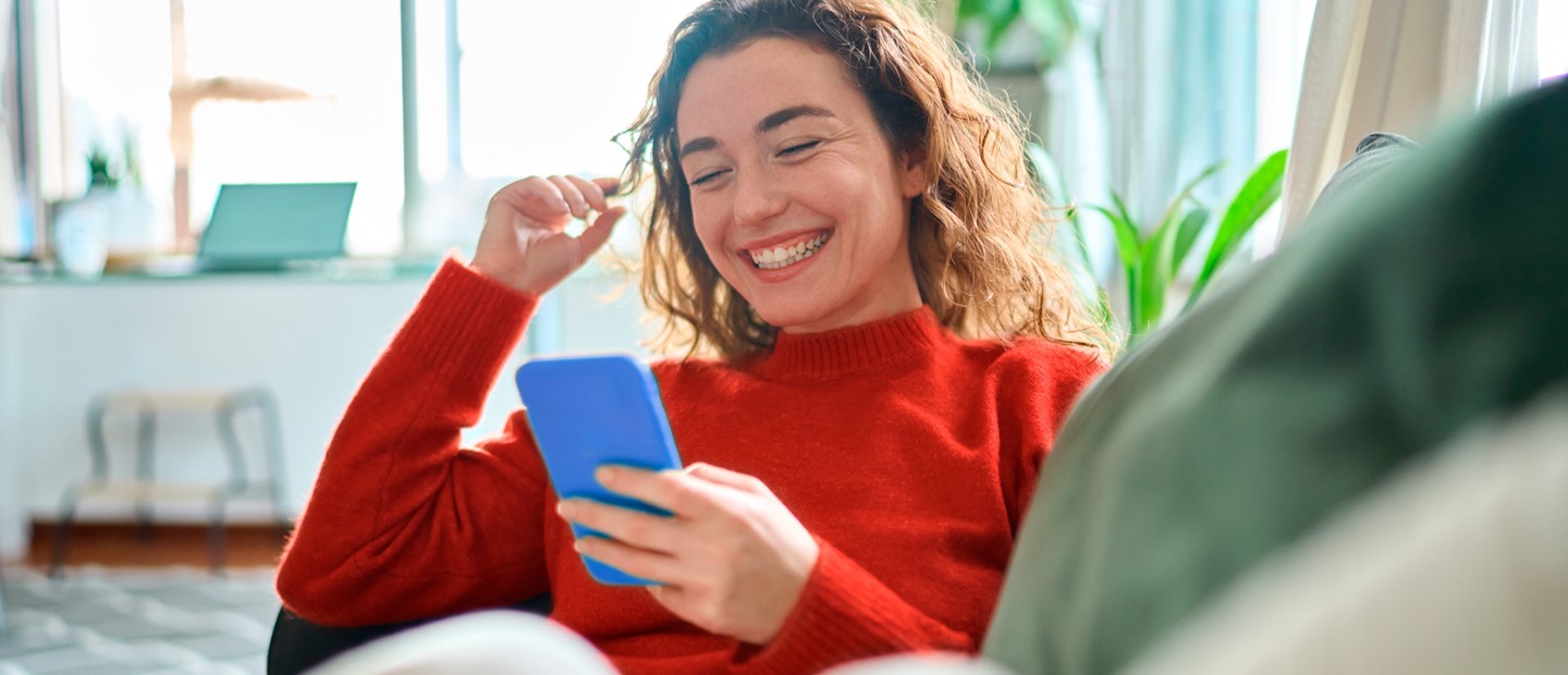 Chica realizando compras online con Bizum desde el sofá de su casa.