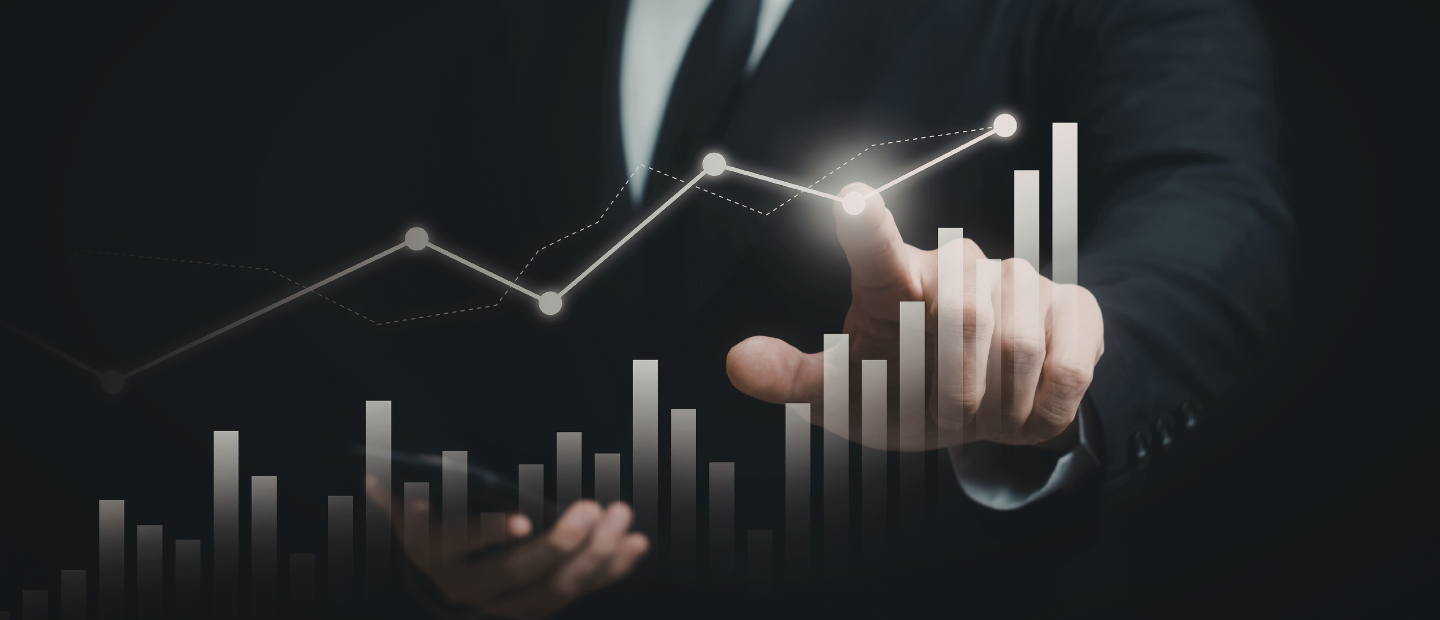 Una mano masculina señalando sobre una pantalla de cristal en la qu se proyectan unos gráficos