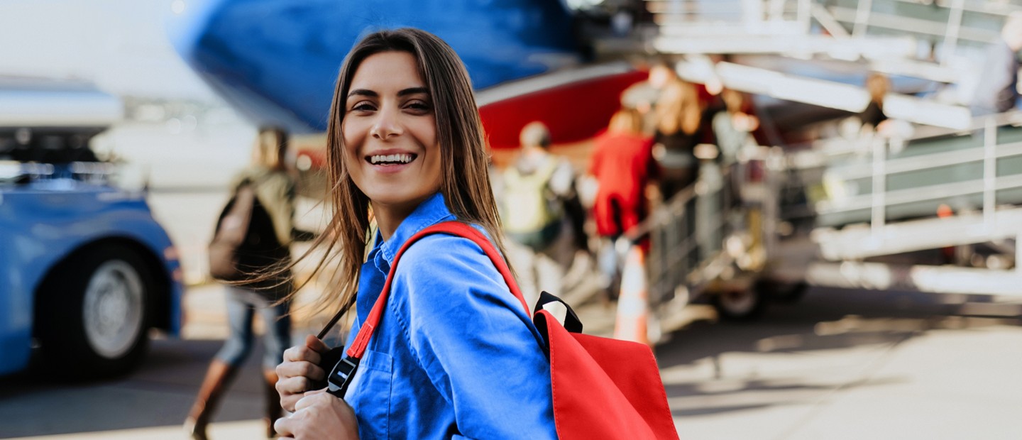 Chica joven alegre a punto de embarcar en un avión.
