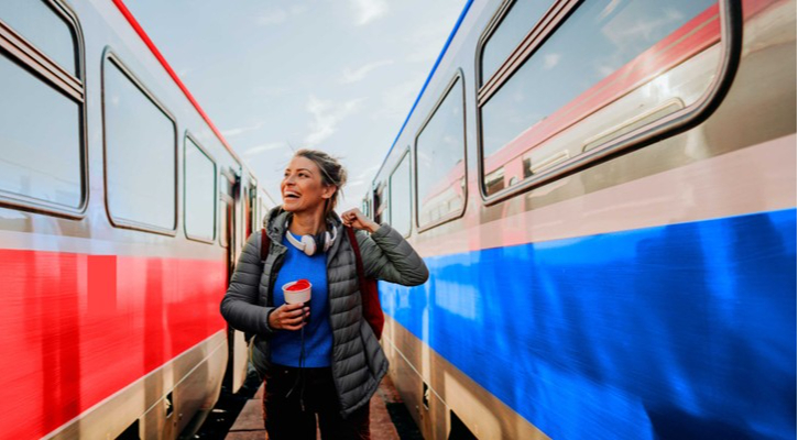 Joven camina entre dos trenes