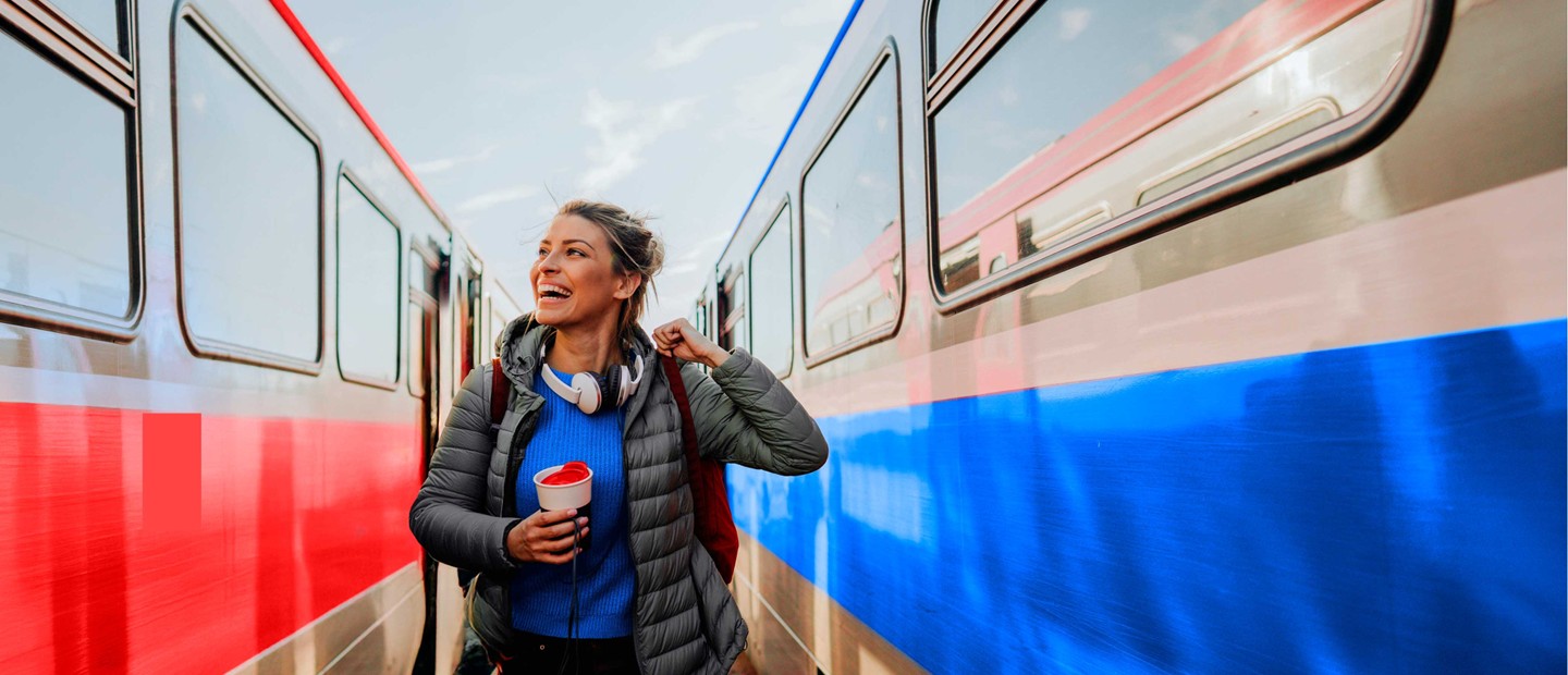 Joven viajera sonriente junot a dos vagones de tren.