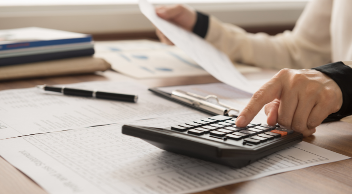 Persona haciendo cálculos con calculadora y papeles sobre una mesa