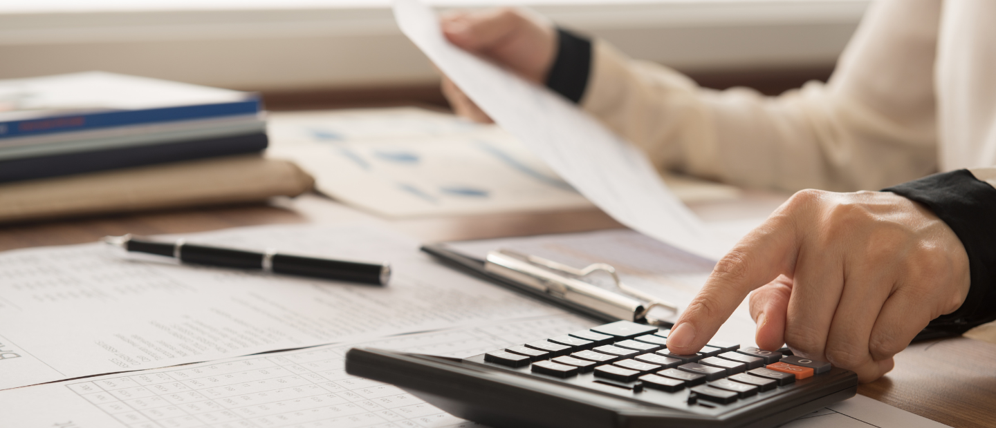 Una persona haciendo cálculos con calculadora y papeles sobre una mesa